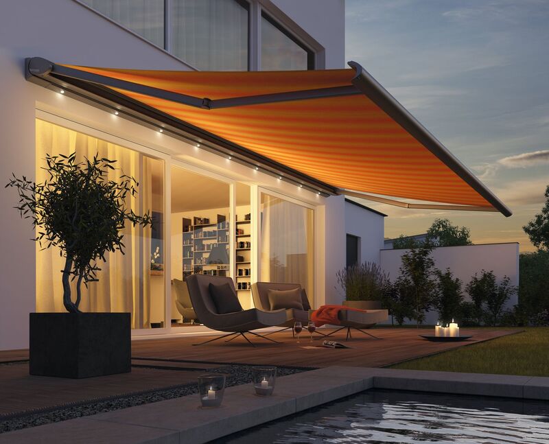 An orange awning extends over a modern terrace area, illuminating the space with warm light.