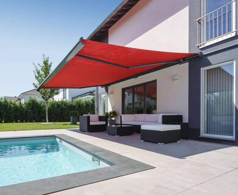 A vibrant red awning covers a modern terrace with a pool and seating area.
