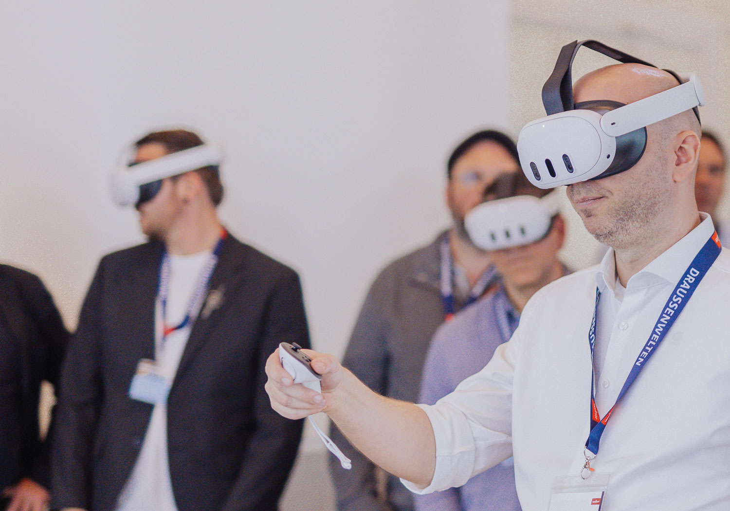 Person mit VR-Brille, die auf einen Bildschirm schaut, umgeben von weiteren Personen mit VR-Brillen.