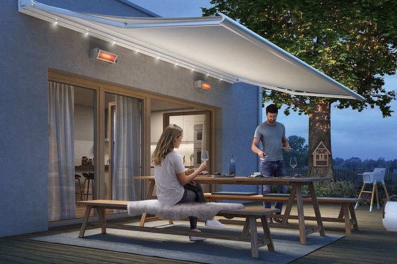 Eine Familie genießt den Abend unter einer Markise auf der Terrasse. Sanftes Licht und gemütliche Atmosphäre.