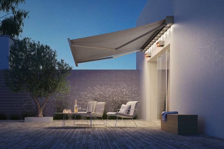 Sonnenmarkise in einem modernen Terrassensituation mit Holzfußboden und Bäumen im Hintergrund.