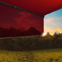 Sonnenuntergang hinter einer rot gefärbten Markise, mit grüner Landschaft im Vordergrund.