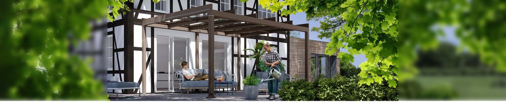 Gemütliche Terrassensituation unter einer kubischen Überdachung an einem Fachwerkhaus mit grünen Pflanzen im Vordergrund. 
