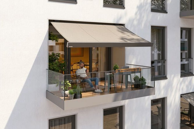 Een moderne gevel met een balkon, een zonnescherm en een zitruimte. Lichtgrijze en witte kleuren domineren.