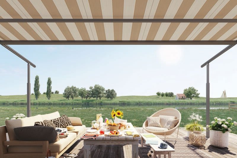 Hellbeige Markisentuch über einer einladenden Terrassensituation mit Sitzgelegenheiten und farbenfrohen Dekorationen.