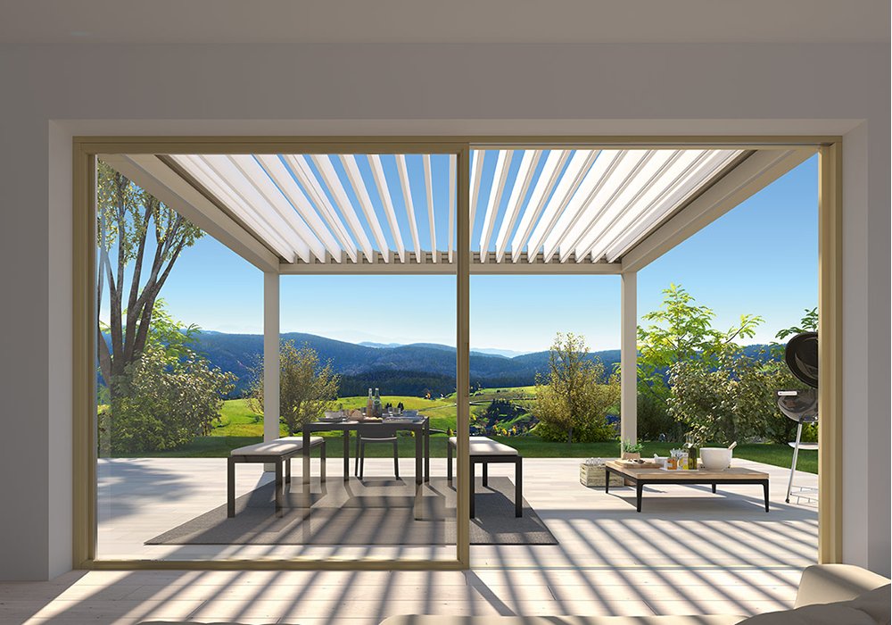 Terrassensituation mit Überdachung, Glas-Schiebewänden und Blick auf die Landschaft. Helle Farben dominieren das Bild.