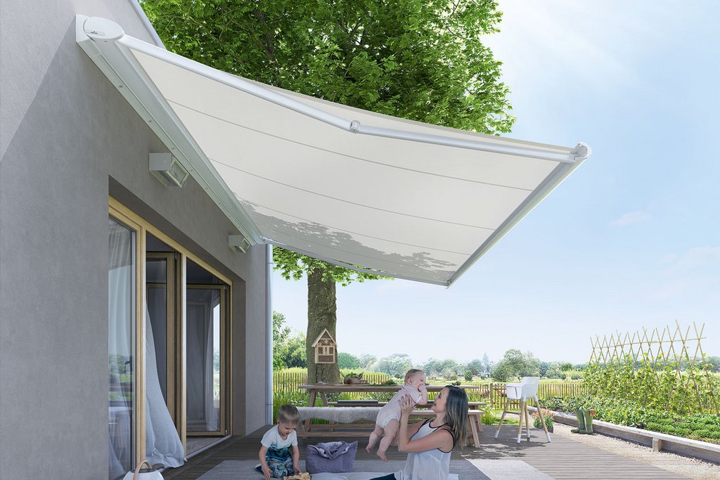 Markise schützt eine Terrassensituation mit Familie, umgeben von Grünflächen und Sonnenlicht.