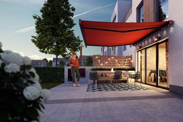 Sonnenschutz in Rot über einer modernen Terrassensituation mit Sitzbereich und Pflanzen im Vordergrund.