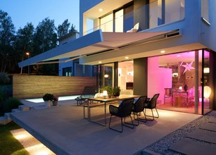 Moderne woning met overdekte terrassituatie en sfeervolle verlichting in een rustige omgeving. 