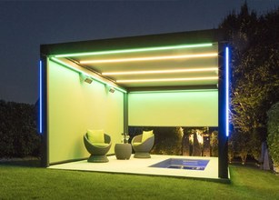 Moderne overkapping met groene verlichting, lounge meubels en een zwembadje in een tuinomgeving. 