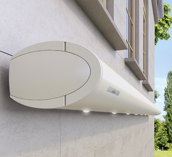 Markisenkasten in rundem Design, hellbeige, montiert an einer Wand mit Fenster und grünem Umfeld.