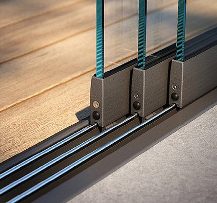 Detailansicht von Glas-Schiebewänden auf einem Holz- und Betonboden mit Metallrahmen.