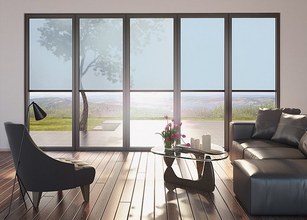 Moderne woonkamer met grote glazen elementen, een elegante fauteuil en een tafel met decoratieve items. 