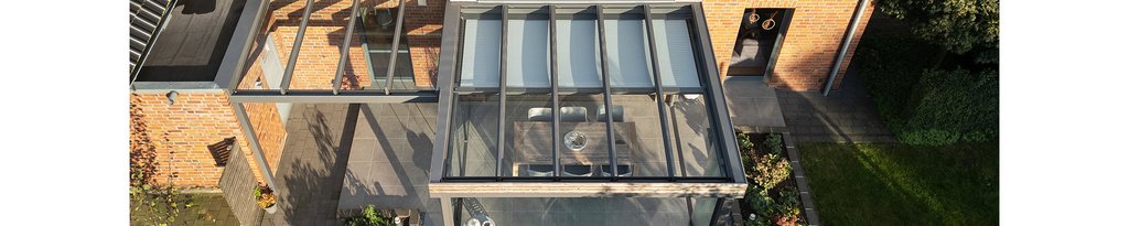 Glasüberdachung über einer Terrassensituation mit moderner Architektur und Holzverkleidung.