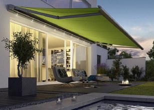 Moderne overdekte terrassensituatie met een heldergroene zonnescherm en comfortabele stoelen in de avondverlichting. 