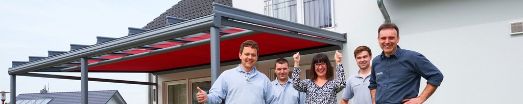 Eine Gruppe von fünf Personen vor einer Überdachung mit rotem Markisentuch.