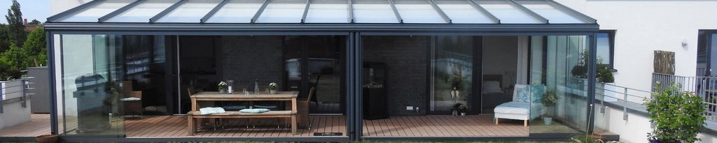 Glas-Wintergarten mit rechteckiger Form, verglaster Fassade und transparentem Dach. Glas-Wintergarten mit rechteckiger Form, verglaster Fassade und transparentem Dach.