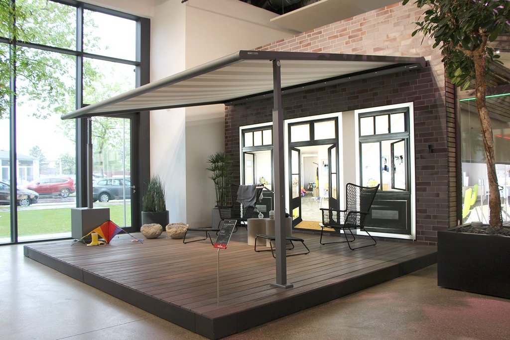 Terrassensituation mit Überdachung, Glas-Schiebewänden und großen Fenstern in einer modernen Umgebung.