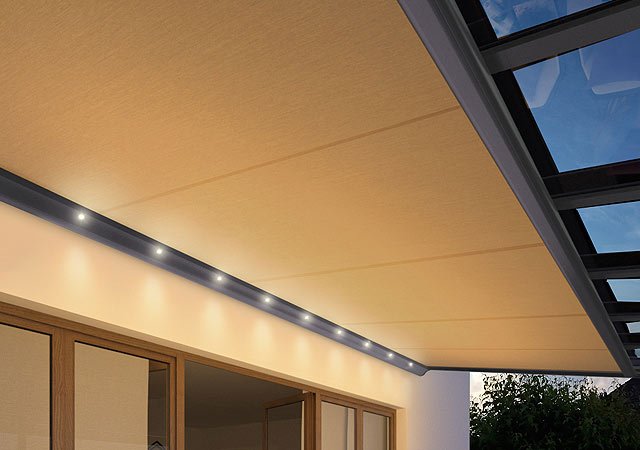 Markisenkasten mit LED-Spots und Überdachung aus hellem Markisentuch, Sicht auf Glasdach und Fenster.