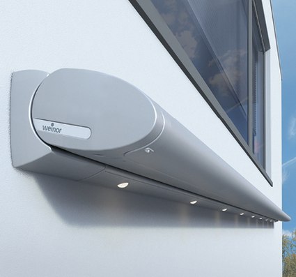 zonneschermkast in zilver met geïntegreerde LED-spots, bevestigd aan een muur naast een raam.